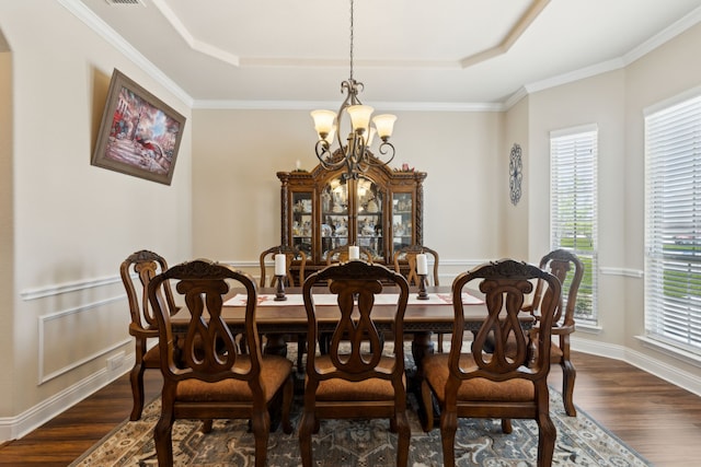 dining space with a tray ceiling, crown molding, an inviting chandelier, and dark wood-style floors