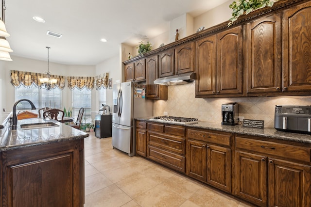 kitchen with tasteful backsplash, under cabinet range hood, visible vents, stainless steel appliances, and a sink