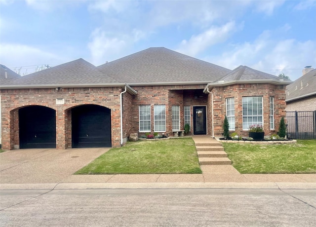 view of front of house with roof with shingles, fence, a front lawn, an attached garage, and concrete driveway