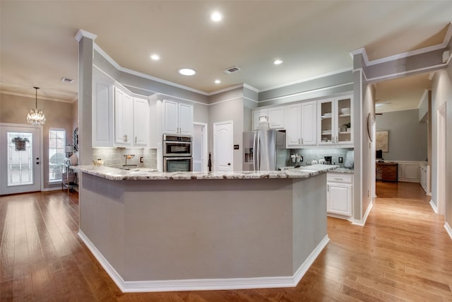 kitchen with crown molding, a peninsula, white cabinetry, visible vents, and appliances with stainless steel finishes