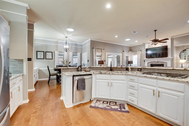 kitchen with stainless steel appliances, a fireplace, ceiling fan with notable chandelier, and white cabinetry