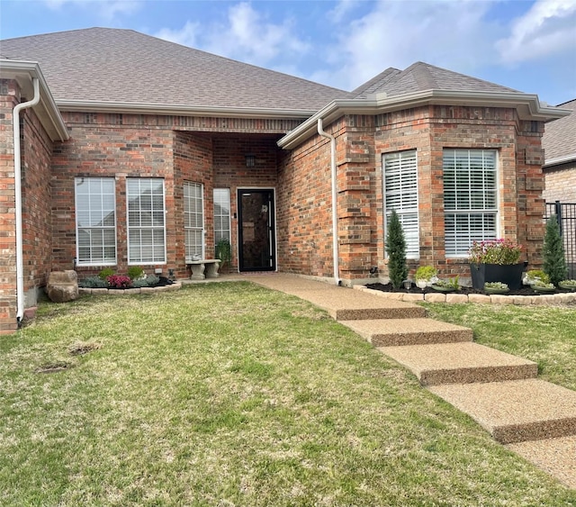 single story home featuring a shingled roof, a front lawn, and brick siding