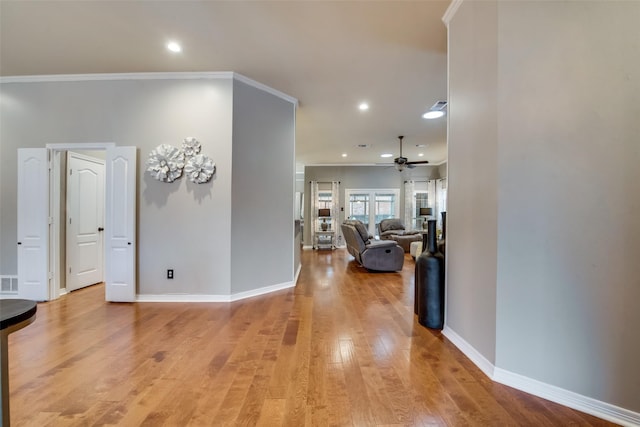 corridor featuring light wood-style flooring, baseboards, ornamental molding, and recessed lighting