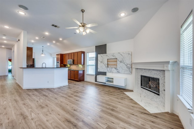 kitchen featuring brown cabinetry, stainless steel appliances, visible vents, open floor plan, and dark countertops