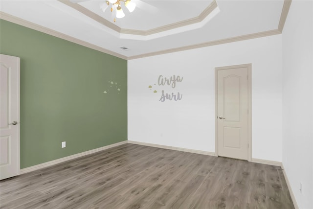 spare room featuring baseboards, ceiling fan, wood finished floors, and a raised ceiling