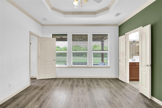 empty room featuring a tray ceiling, visible vents, a healthy amount of sunlight, and ceiling fan