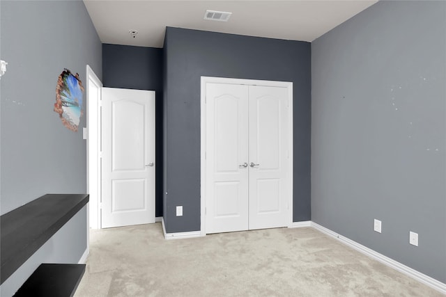 unfurnished bedroom featuring light colored carpet, baseboards, visible vents, and a closet