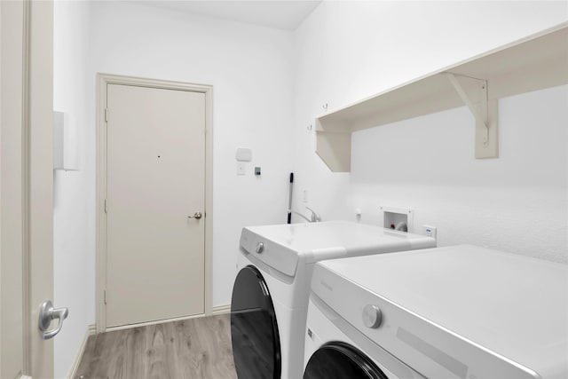 laundry room with baseboards, laundry area, washer and clothes dryer, and light wood finished floors