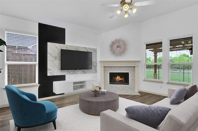 living room featuring baseboards, a ceiling fan, wood finished floors, and a premium fireplace