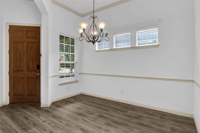 unfurnished dining area with arched walkways, baseboards, an inviting chandelier, and wood finished floors