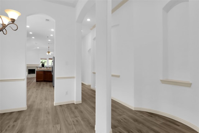 interior space featuring arched walkways, baseboards, recessed lighting, and light wood-type flooring