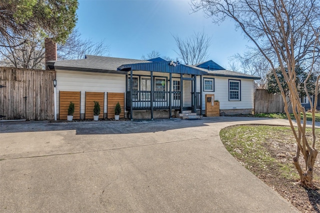 view of front of property with concrete driveway, a chimney, covered porch, and fence
