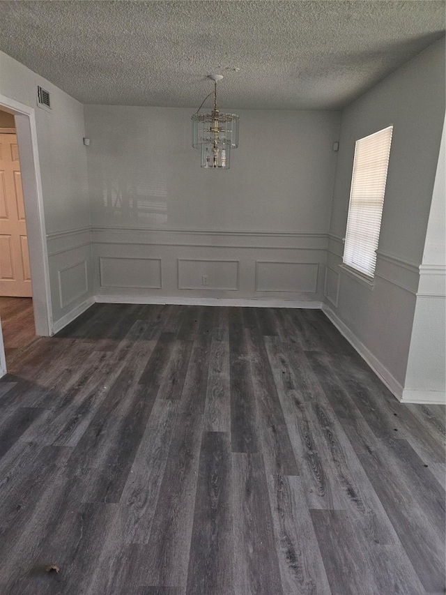 7211 Arborcrest Dr, Dallas, TX 75232 - unfurnished dining area featuring visible vents, dark wood-style floors, an inviting chandelier, and a textured ceiling