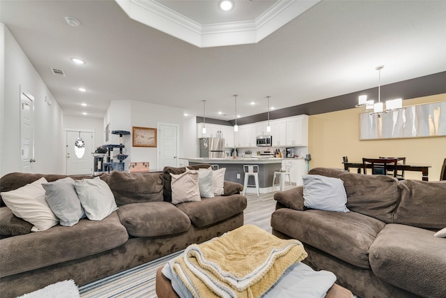living area with light wood-style floors, crown molding, recessed lighting, a chandelier, and a raised ceiling