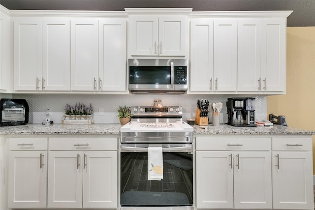 kitchen with white cabinets, light stone countertops, and stainless steel appliances