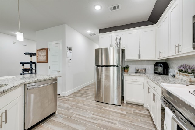kitchen featuring visible vents, appliances with stainless steel finishes, white cabinetry, backsplash, and light wood-style flooring