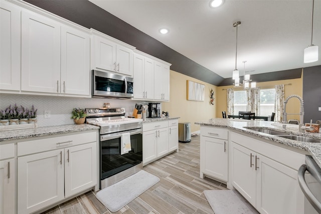 kitchen with white cabinets, appliances with stainless steel finishes, a sink, and vaulted ceiling