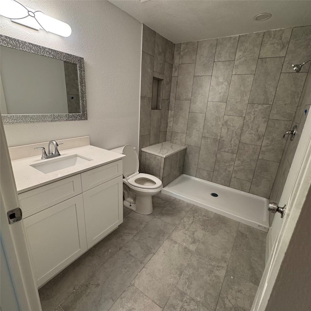 full bath with toilet, a stall shower, vanity, and a textured wall