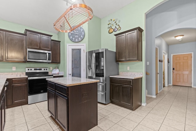 6517 Sierra Madre Dr, Fort Worth, TX 76179 - kitchen with dark brown cabinetry, light tile patterned flooring, a kitchen island, arched walkways, and stainless steel appliances