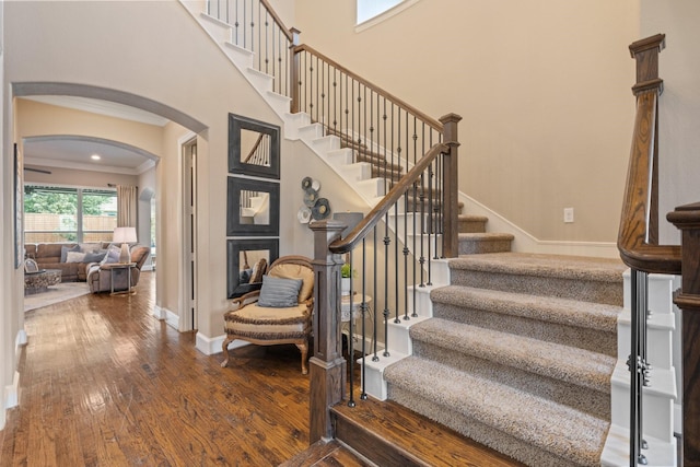 901 Moss Glen Dr, Prosper, TX 75078 - stairs featuring arched walkways, a towering ceiling, baseboards, ornamental molding, and wood-type flooring