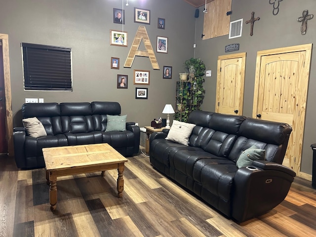 living area with a high ceiling, visible vents, and wood finished floors