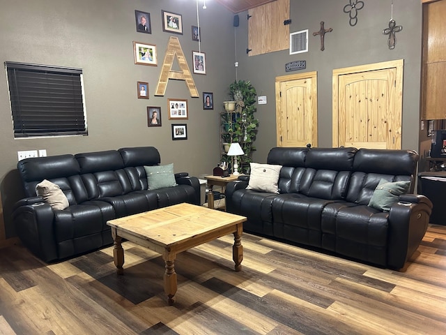 living room with visible vents, wood finished floors, and a high ceiling