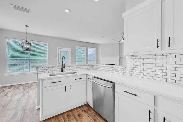 kitchen featuring light countertops, backsplash, dishwasher, a sink, and visible vents