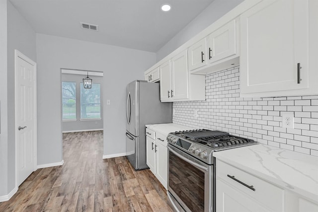 kitchen with light stone countertops, stainless steel appliances, tasteful backsplash, visible vents, and white cabinetry