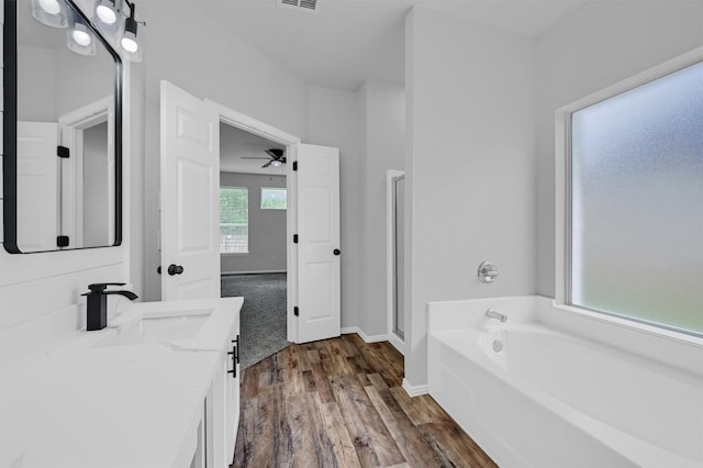 full bathroom with ceiling fan, visible vents, a garden tub, wood finished floors, and vanity