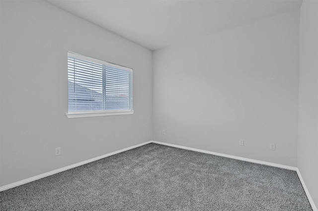 empty room featuring carpet and baseboards