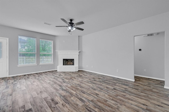 unfurnished living room with ceiling fan, visible vents, baseboards, a fireplace, and wood finished floors