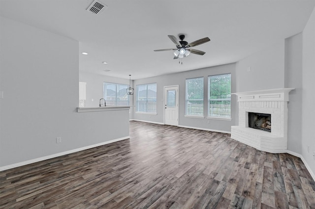 unfurnished living room with ceiling fan, dark wood-style flooring, a fireplace, baseboards, and visible vents