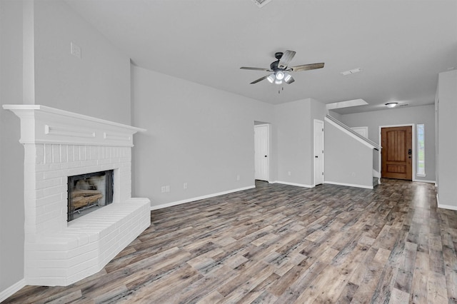 unfurnished living room with a fireplace, wood finished floors, ceiling fan, and baseboards