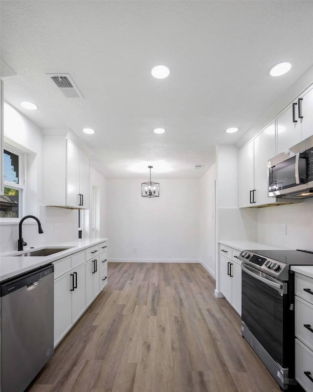 446 Silver Creek Dr, Duncanville, TX 75137 - kitchen featuring stainless steel appliances, a sink, a chandelier, light wood-type flooring, and light countertops