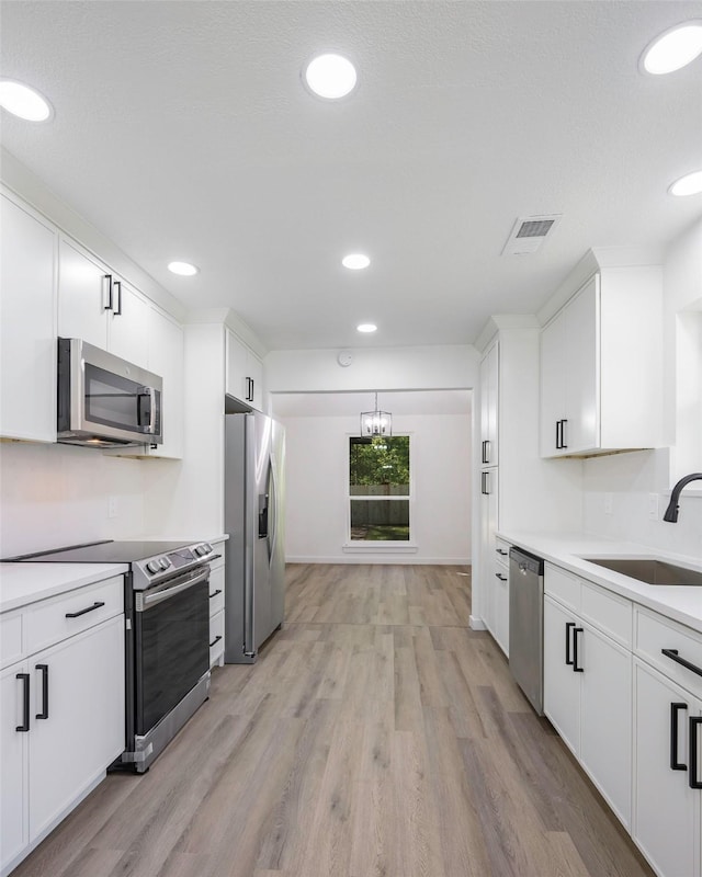 446 Silver Creek Dr, Duncanville, TX 75137 - kitchen with appliances with stainless steel finishes, a sink, light wood-type flooring, white cabinets, and light countertops