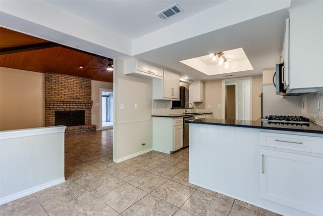 kitchen with dark stone counters, tasteful backsplash, white cabinetry, appliances with stainless steel finishes, and light tile patterned floors