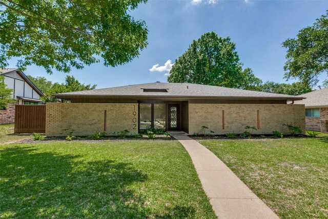 view of front of property with a front lawn, brick siding, and fence