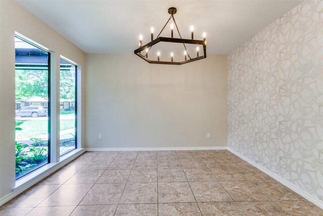 unfurnished dining area with a wainscoted wall, a tray ceiling, a notable chandelier, and light tile patterned floors