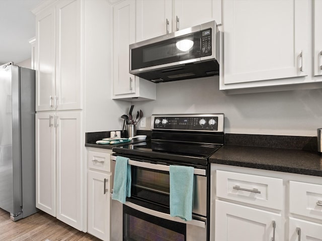kitchen featuring white cabinetry, light wood finished floors, dark countertops, and stainless steel appliances