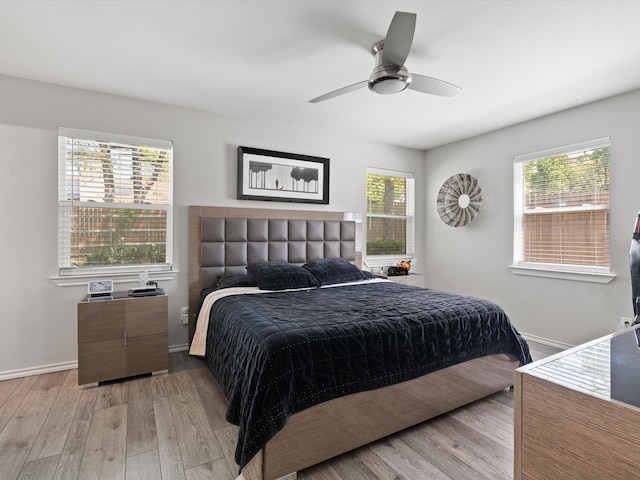 bedroom with a ceiling fan, baseboards, and light wood-style floors