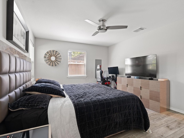 bedroom with ceiling fan, visible vents, and wood finished floors