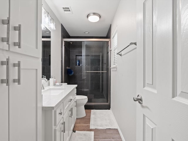bathroom with a stall shower, toilet, visible vents, and vanity