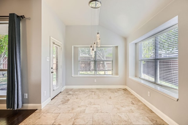 unfurnished dining area featuring baseboards and vaulted ceiling