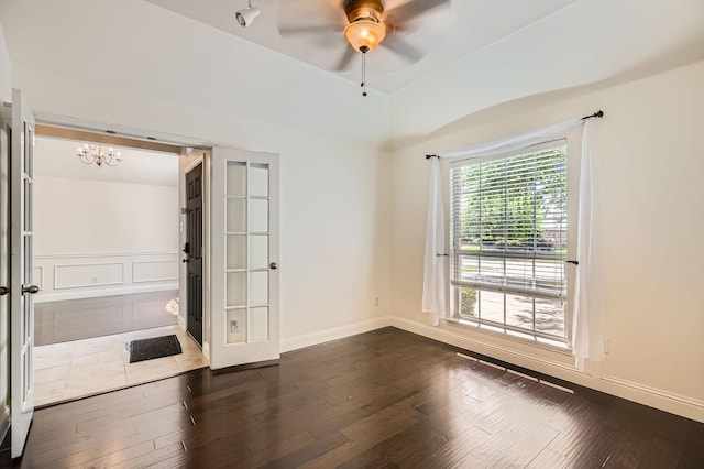 unfurnished room featuring baseboards, ceiling fan with notable chandelier, and dark wood-type flooring