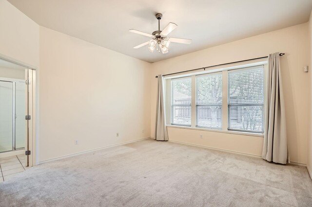 empty room with baseboards, a ceiling fan, and light carpet