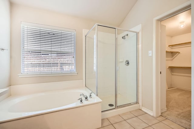 full bath featuring a walk in closet, tile patterned flooring, a stall shower, and a garden tub