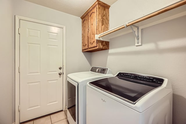 laundry area featuring light tile patterned floors, washing machine and dryer, and cabinet space