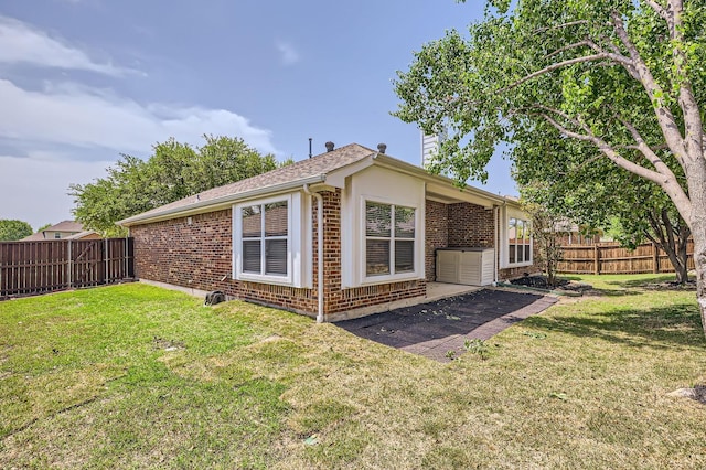 view of property exterior with a fenced backyard, a lawn, and brick siding