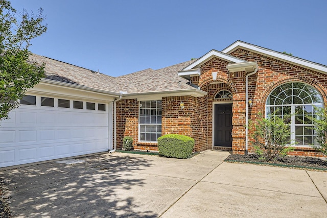 single story home featuring brick siding, a shingled roof, a garage, and driveway