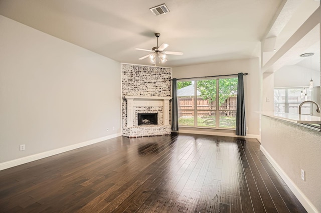 unfurnished living room with a ceiling fan, dark wood-style flooring, visible vents, a fireplace, and baseboards